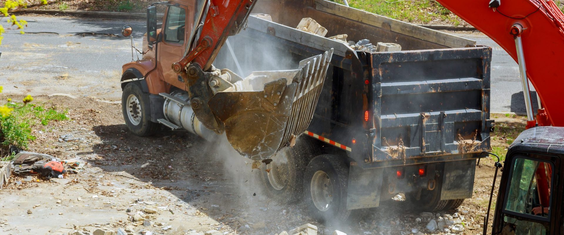 Backhoe excavator scoop loading from building in the construction debris a dump truck